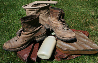July Picture of worn hiking Boots and water bottle on rocks. Image is from the Hike The Bitterroot Big Three Picture Tour.
