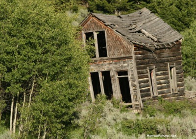 June picture of the front of a log cabin in Castle Town Montana. Image is from the Castle Town Montana Picture Tour.