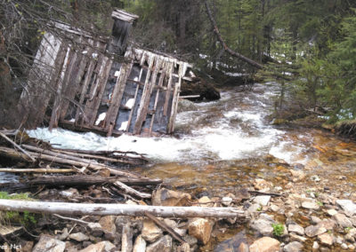 June picture of wooden building partially submerged on Elkhorn Creek in the Coolidge Ghost town. Image is from the Coolidge Montana Picture Tour.