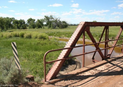 June picture of a metal bridge spanning a creek near the Tongue River. Image is from the Tongue River Picture Tour.